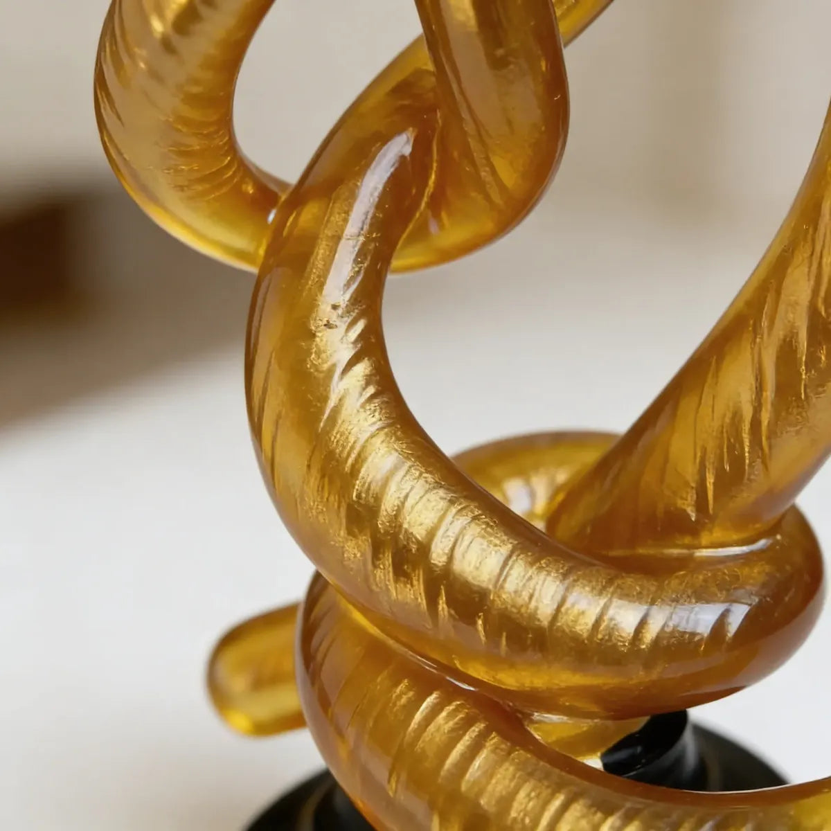 Escultura Decorativa Entrelaçada Dourada com Base Preta em Resina